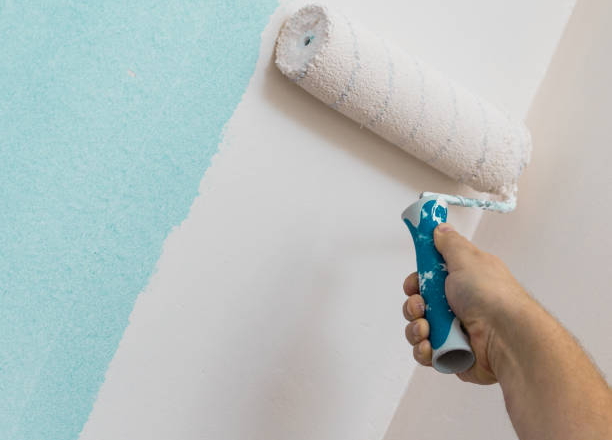 Ручная покраска стены валиком, нанесение светло-голубой краски.